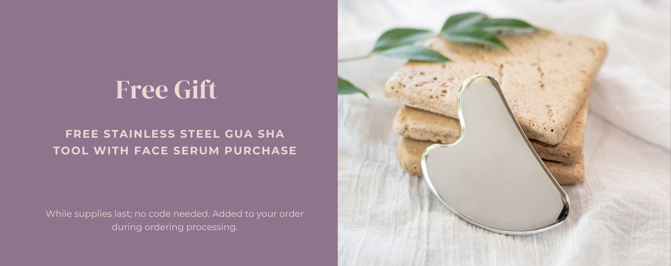 Stainless steelgua sha tool with face serum and cookies on a white surface