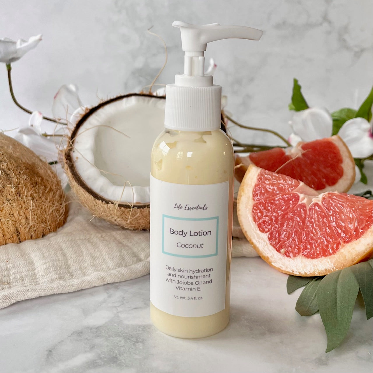 Body lotion bottle with pump on a marble surface with coconut and grapefruit.